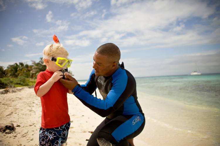 Man helping a boy with a snorkeling mask